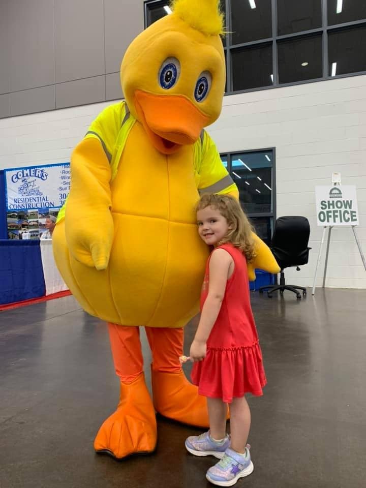 Puddles the duck mascot hugging a young fan