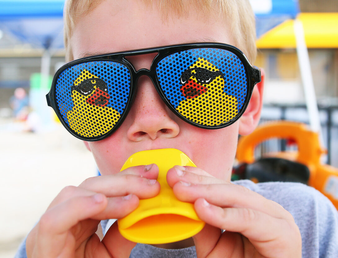 A young fan in duck sunglasses sounding a duck call